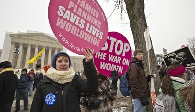 
              Abortion rights protesters hold signs as anti-abortion activists march past the Capitol to the Supreme Court in Washington, Friday, Jan. 25, 2013, as they observe the 40th anniversary o